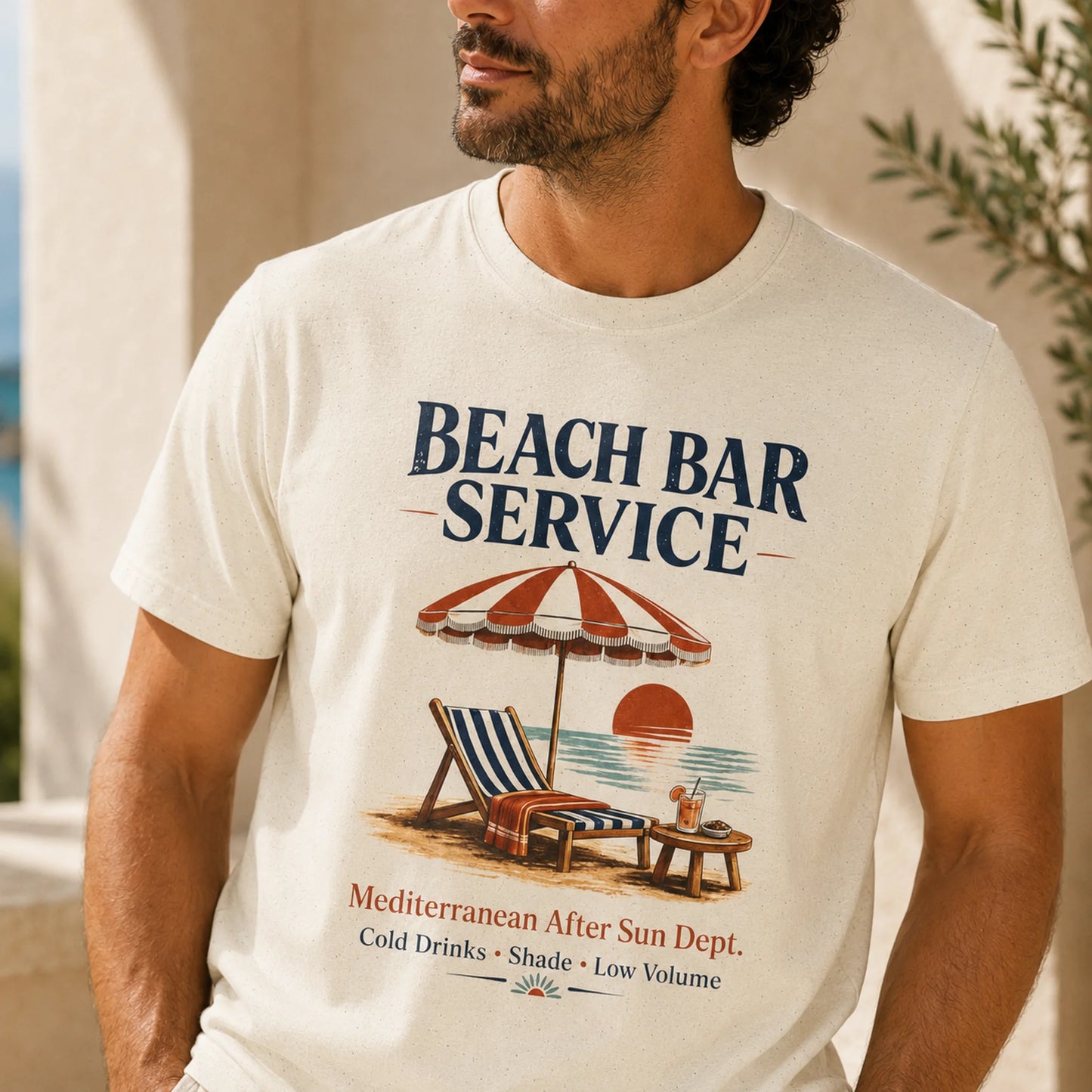 TP HERO: A man wearing a cream-colored graphic t-shirt with a retro 'Beach Bar Service' design featuring a striped beach umbrella, lounge chair, and sunset.