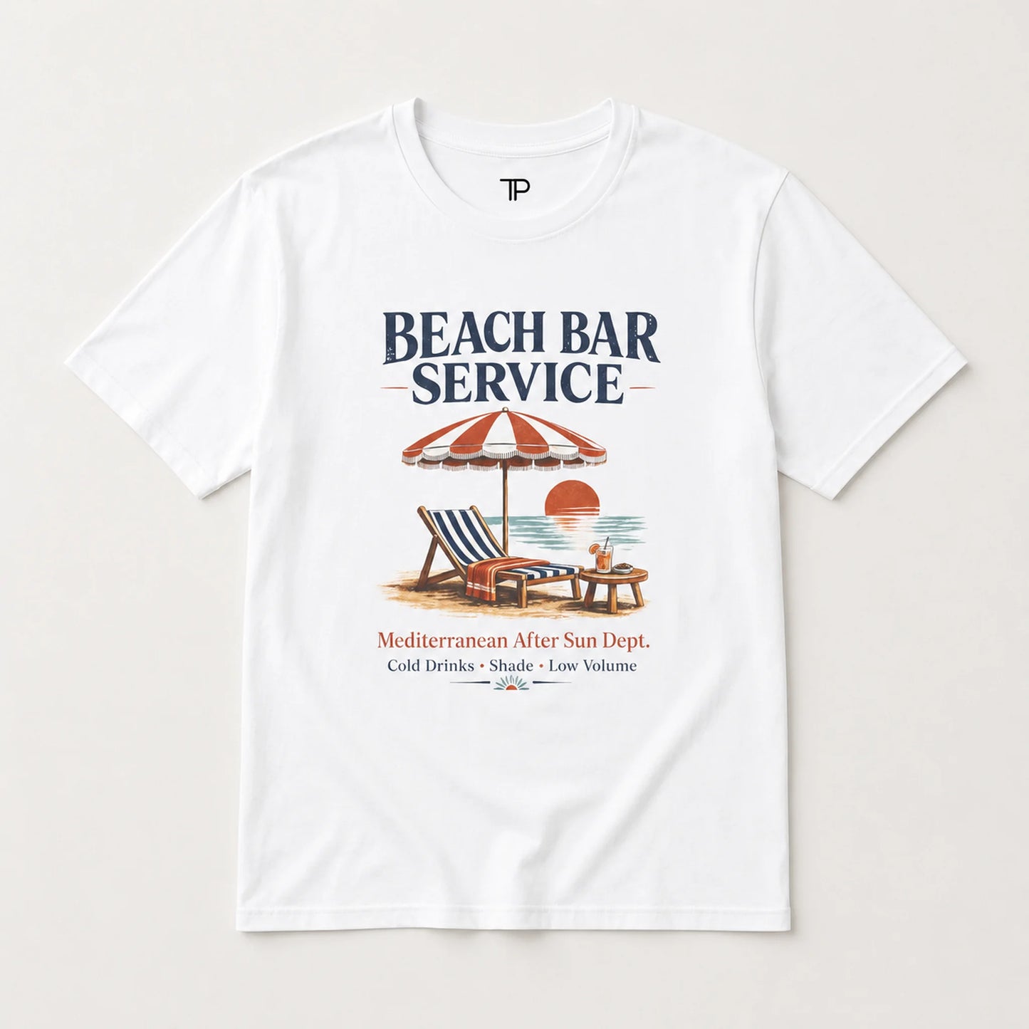 A white short-sleeve crewneck t-shirt featuring a retro-style graphic print of a beach bar scene with the text 'BEACH BAR SERVICE' and a vintage illustration of a striped umbrella, lounge chair, and sunset.