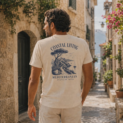 Man wearing a 'Coastal Living' t-shirt walking down a scenic street.