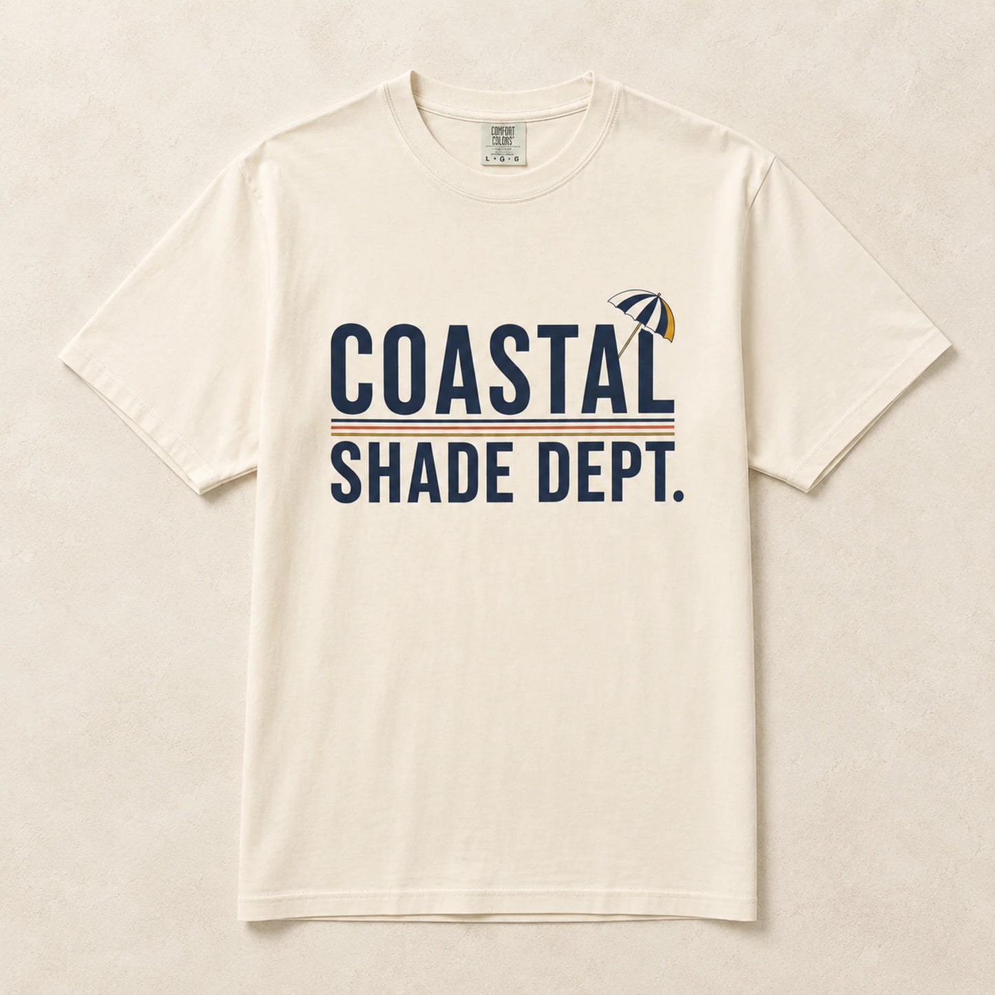 Ivory Coastal Shade Dept graphic T-shirt laid flat with retro beach umbrella artwork