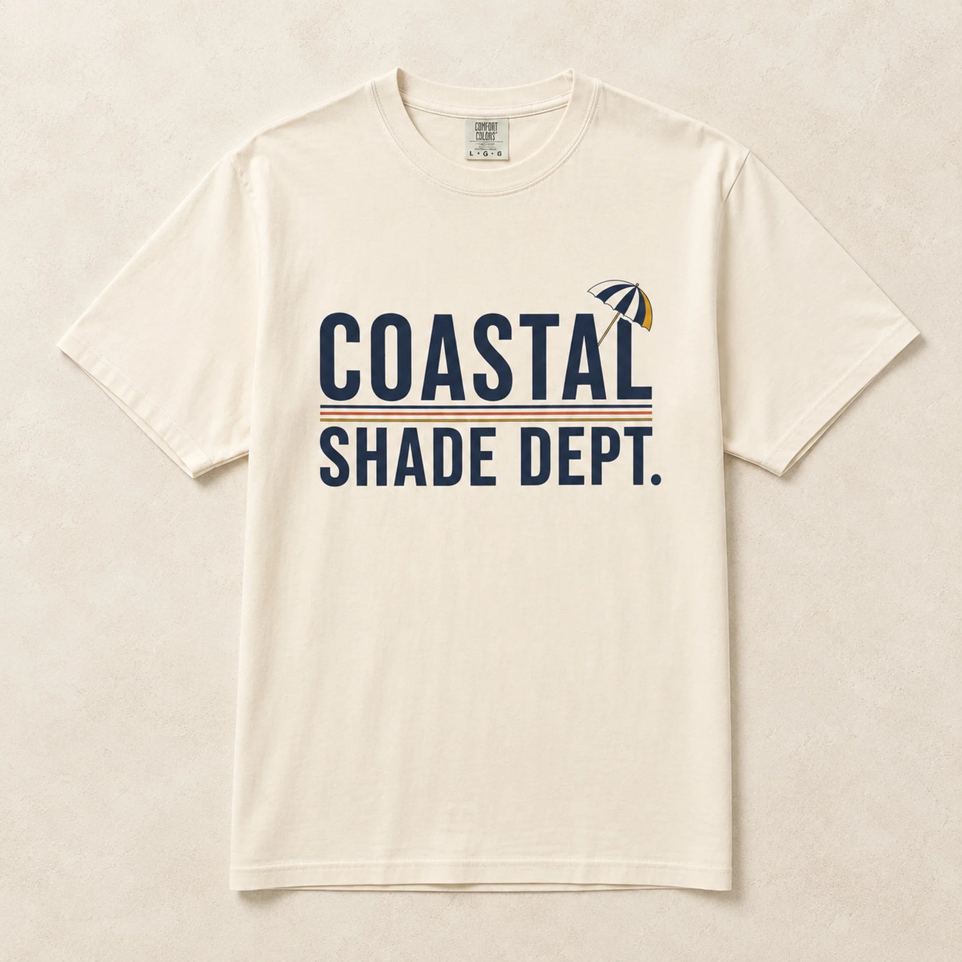 Ivory Coastal Shade Dept graphic T-shirt laid flat with retro beach umbrella artwork