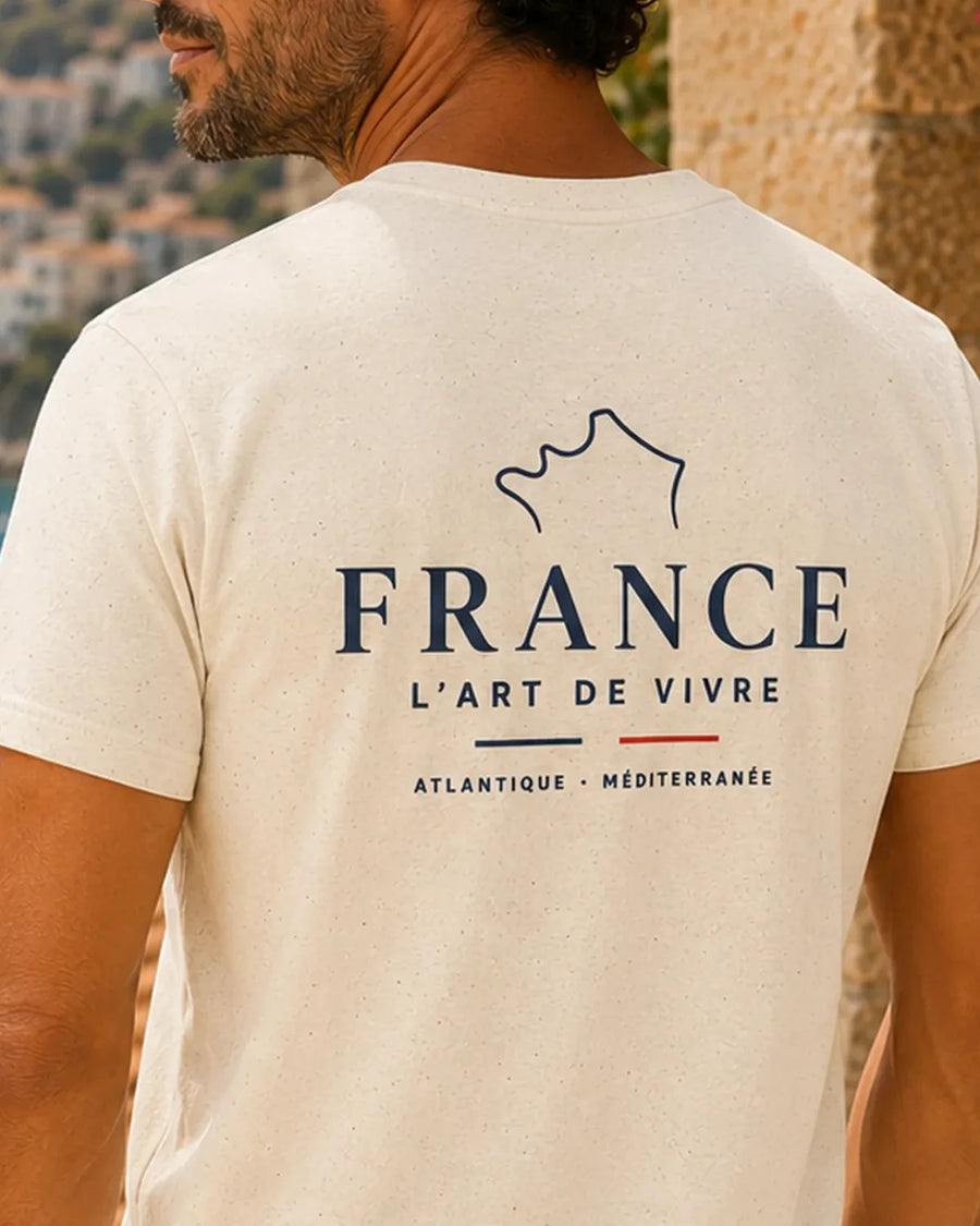 Adult model wearing the Natural France L’Art de Vivre unisex T-shirt, showing the compact navy and red left-chest print.