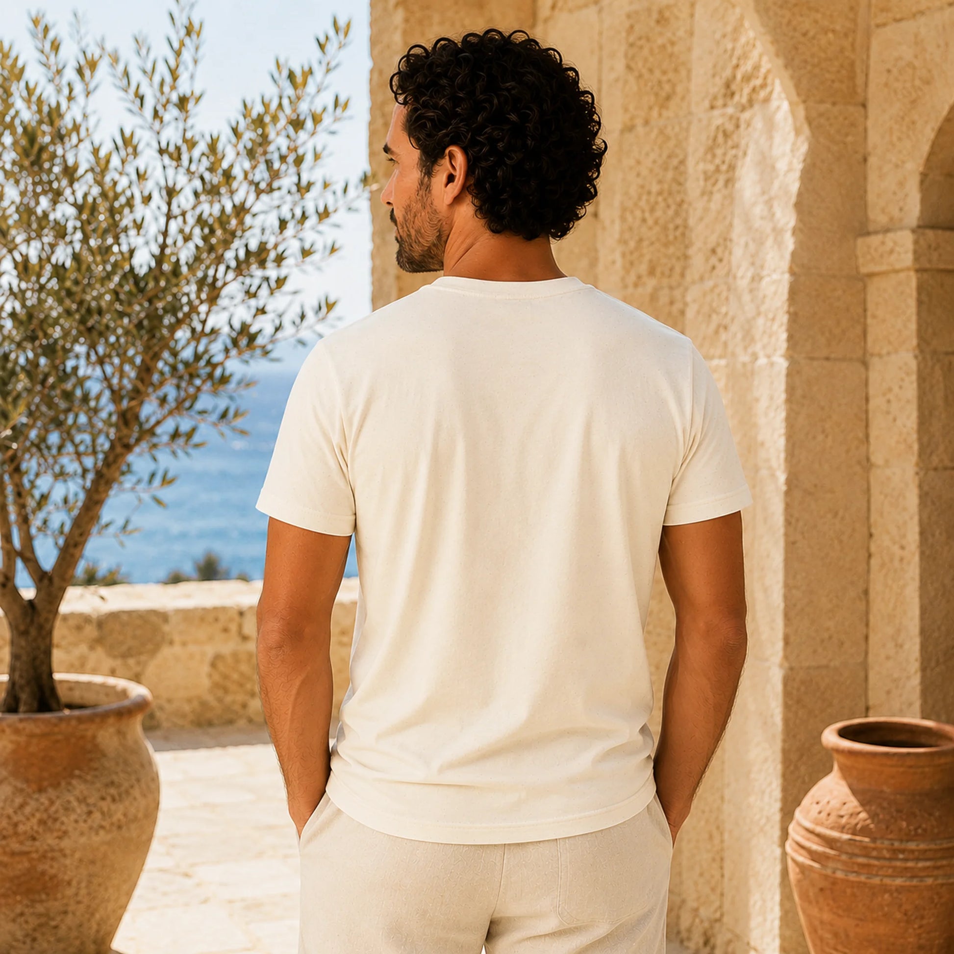 Man in a white t-shirt standing outdoors with a scenic background