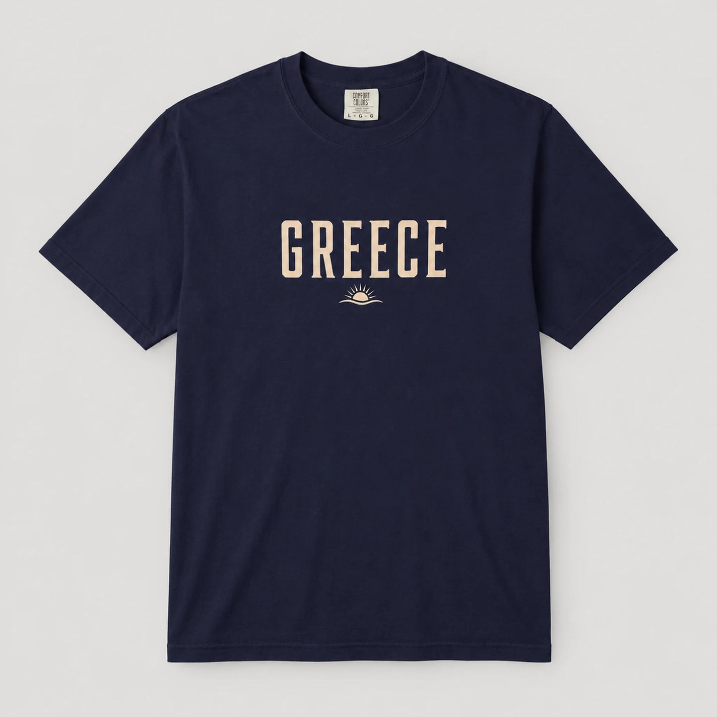 A navy blue short-sleeve crewneck t-shirt with 'GREECE' printed in beige block letters and a small sun graphic on the chest, displayed flat against a light gray background.