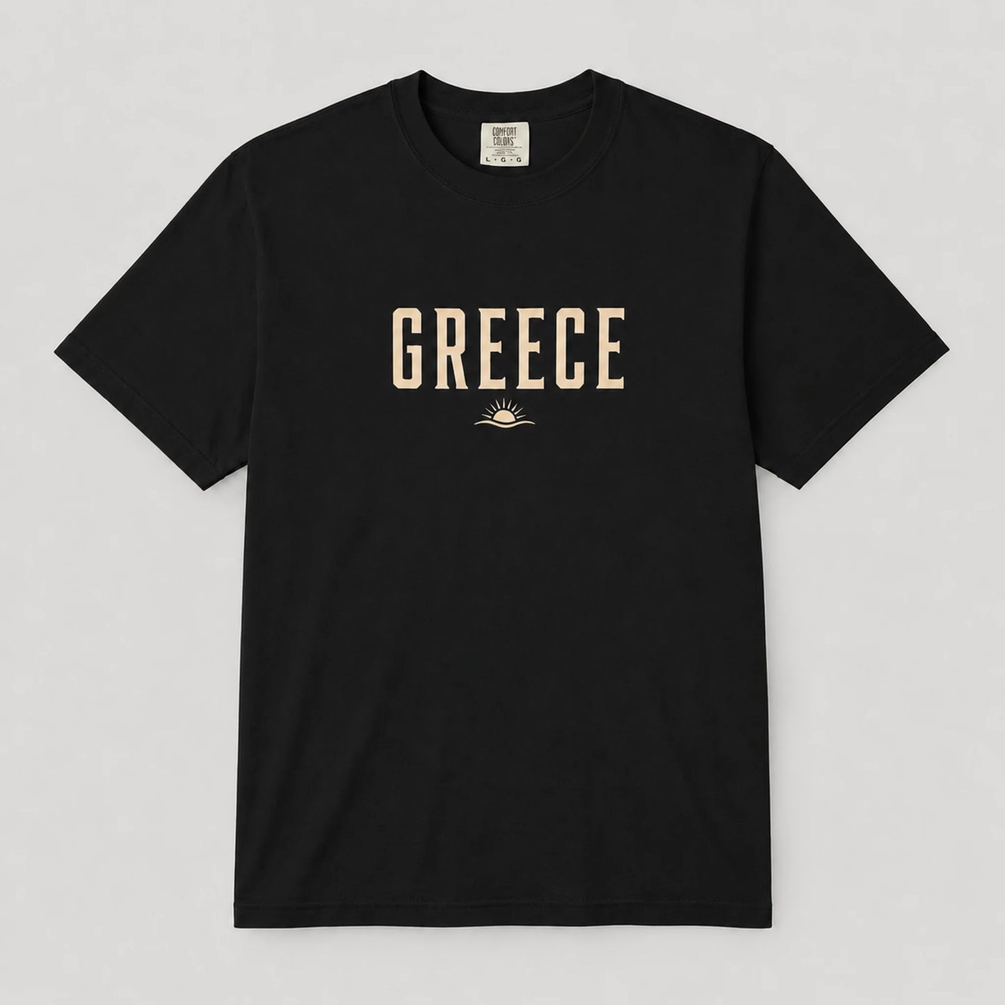 A black short-sleeve crewneck t-shirt with 'GREECE' printed in beige block letters across the chest, featuring a small sun graphic underneath, displayed on a neutral light gray background.