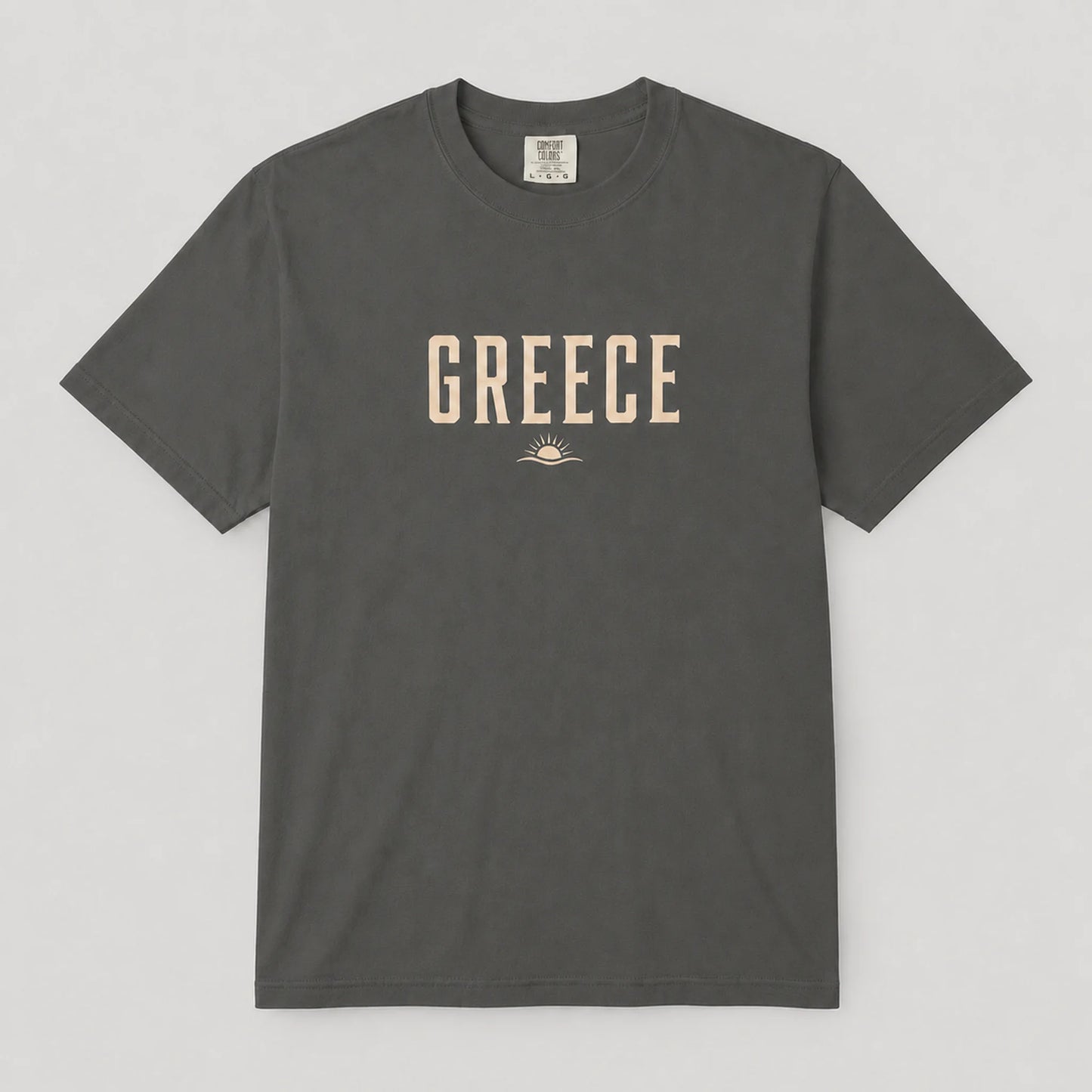 A dark gray crewneck t-shirt with 'GREECE' printed in beige block letters and a small sun graphic on the chest, displayed flat against a light gray background.