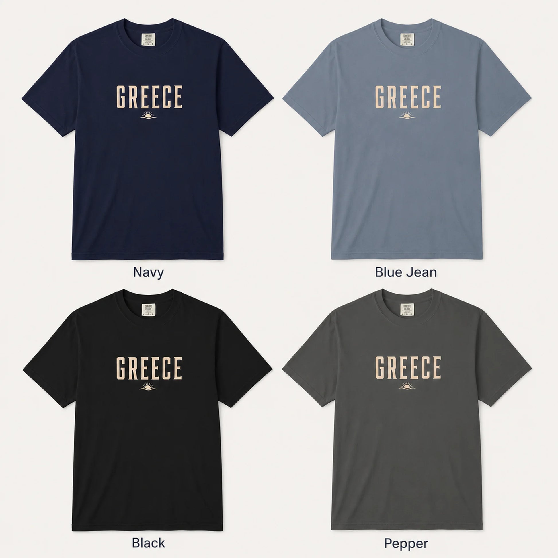 Four short-sleeve crew-neck T-shirts shown in a 2x2 grid on a light gray background, labeled Navy, Blue Jean, Black, and Pepper. Each shirt has a large 'GREECE' graphic across the chest in a muted beige tone with a small emblem below.