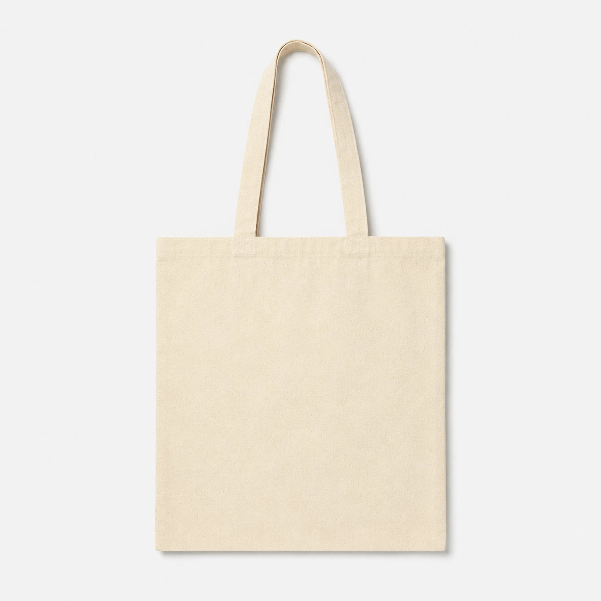 A plain canvas tote bag in a light cream or off-white color, featuring two long shoulder straps, shown against a solid light gray background.