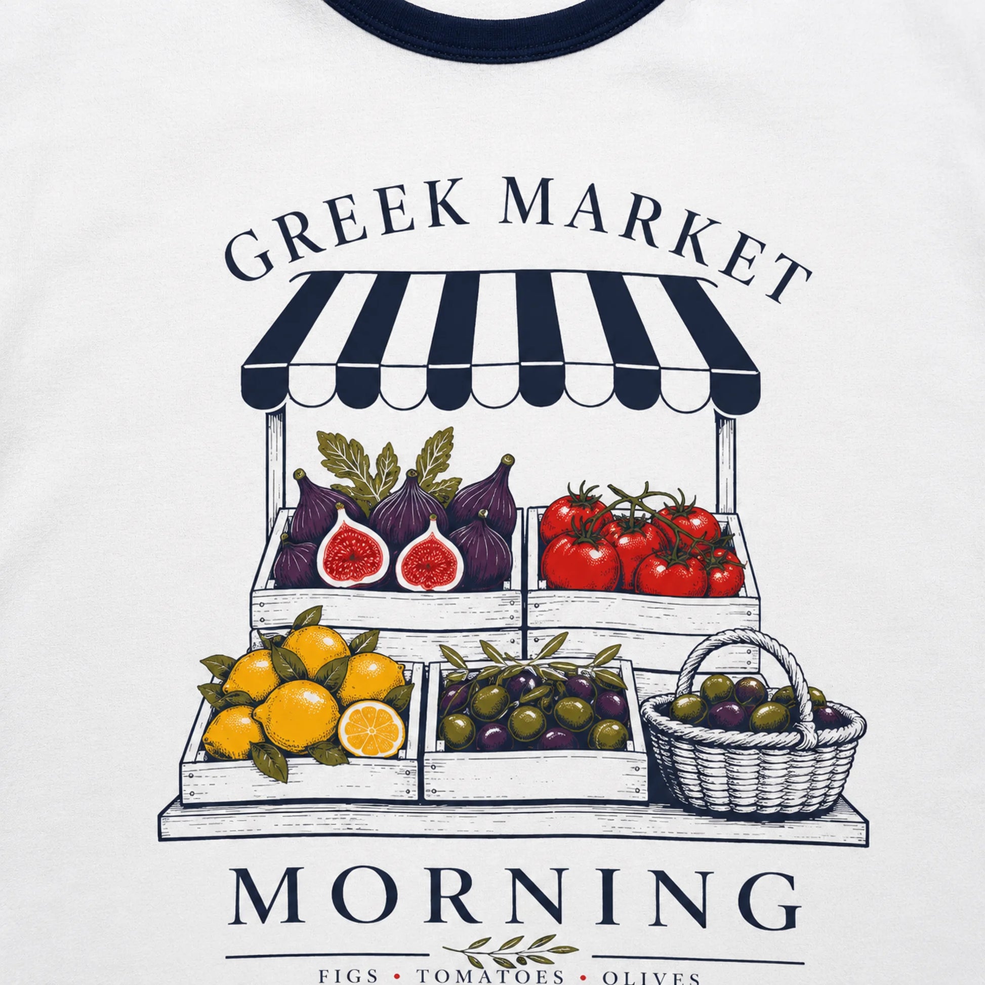 White ringer t-shirt featuring a graphic print of a Greek market morning fruit and vegetable stand with figs, tomatoes, lemons, olives, and a basket, under the text 'GREEK MARKET MORNING'.