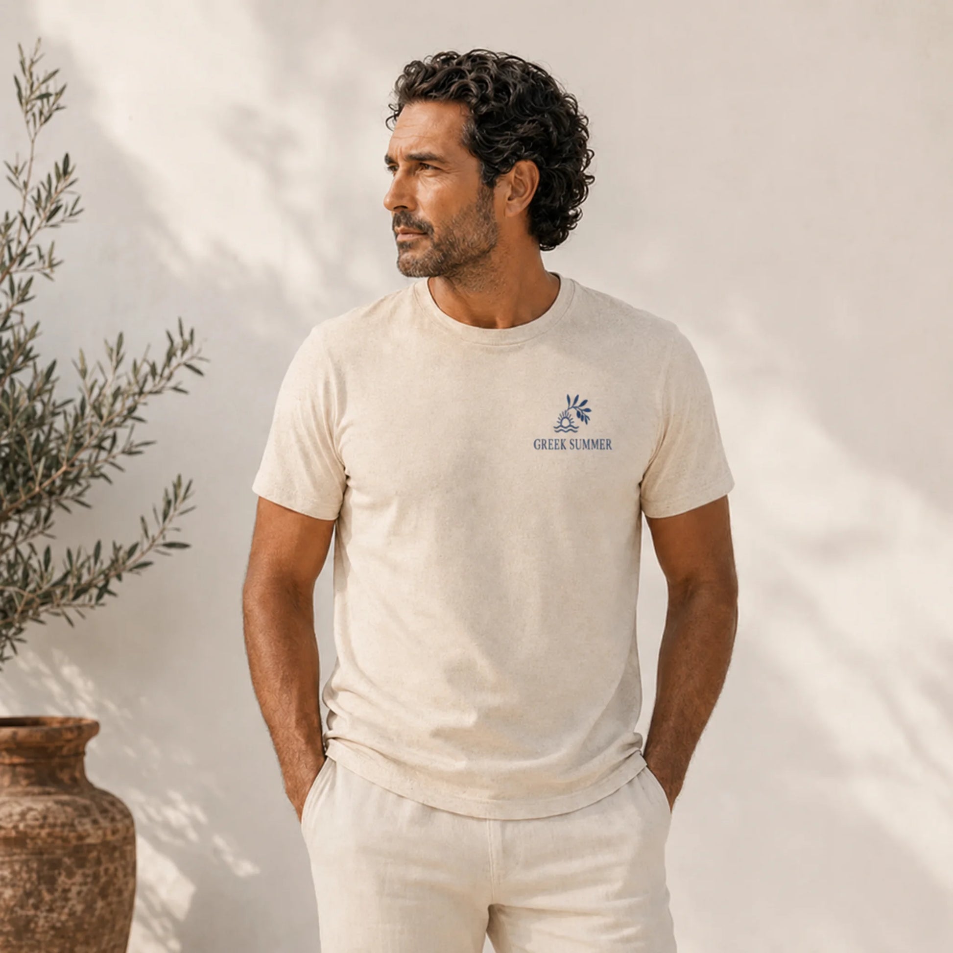 Man wearing a beige t-shirt with a logo, standing against a neutral background.