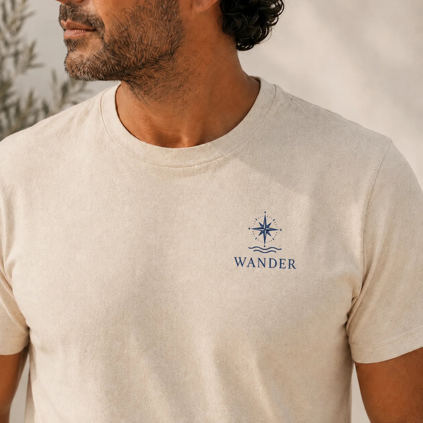 Man wearing a beige t-shirt with a 'Wander' logo on a plain background