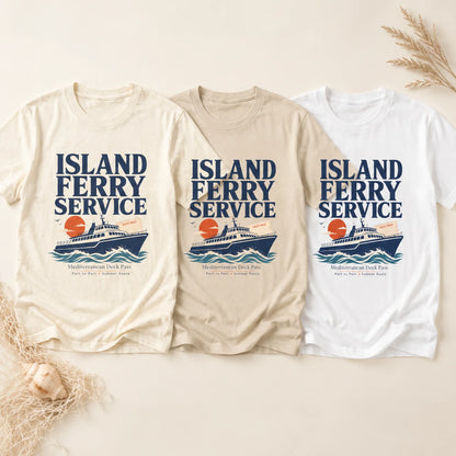 Three short-sleeve graphic T-shirts laid flat on a light beige background with decorative dried grass and shells. The shirts are shown in cream, tan, and white, each printed with the text 'ISLAND FERRY SERVICE' above a ferry illustration and smaller destination text.