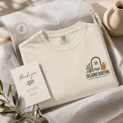 Beige t-shirt with 'Island Routine' logo, card, and decorative elements on a neutral background