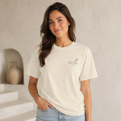 Woman wearing a white t-shirt with a logo, standing in a neutral indoor setting.
