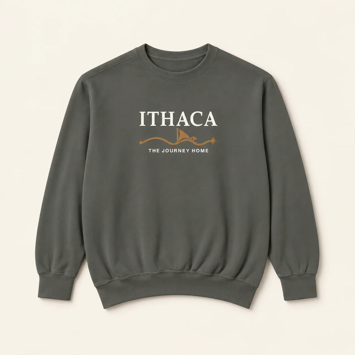 A dark gray crewneck sweatshirt with 'ITHACA' and 'THE JOURNEY HOME' embroidered in white on the chest, accented by a small orange graphic, shown against a light beige background.