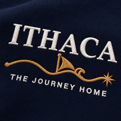 Close-up of embroidered text reading 'ITHACA' in white, a gold sailboat and wave motif, and 'THE JOURNEY HOME' in white on a dark navy fabric background.