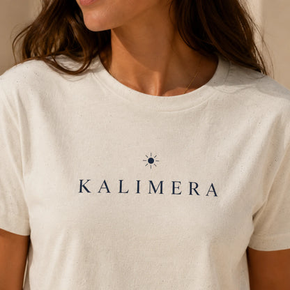TP HERO: A close-up of a woman wearing a natural color crewneck t-shirt with the brand name 'KALIMERA' printed in navy blue text and a small sun icon on the chest.
