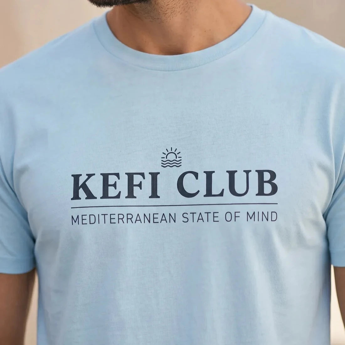 TP HERO: Light blue t-shirt with 'KEFI CLUB' text and logo on a plain background