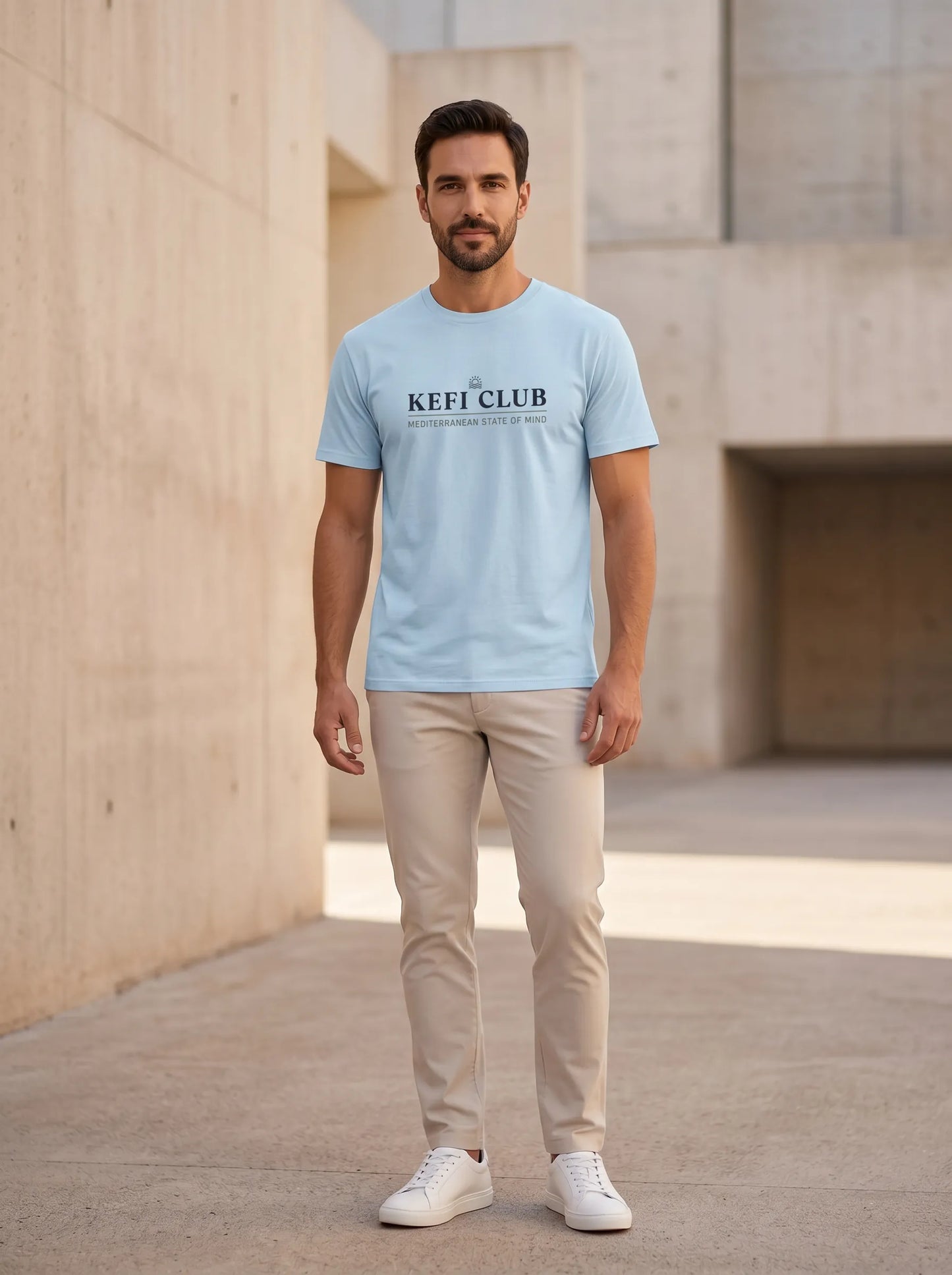 Male model wearing Kefi Club light blue T-shirt in a clean urban lifestyle setting