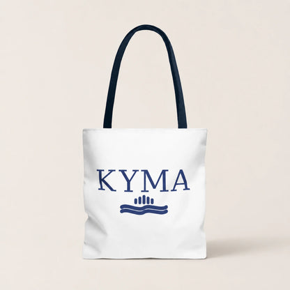 White tote bag with 'KYMA' branding on a beige background