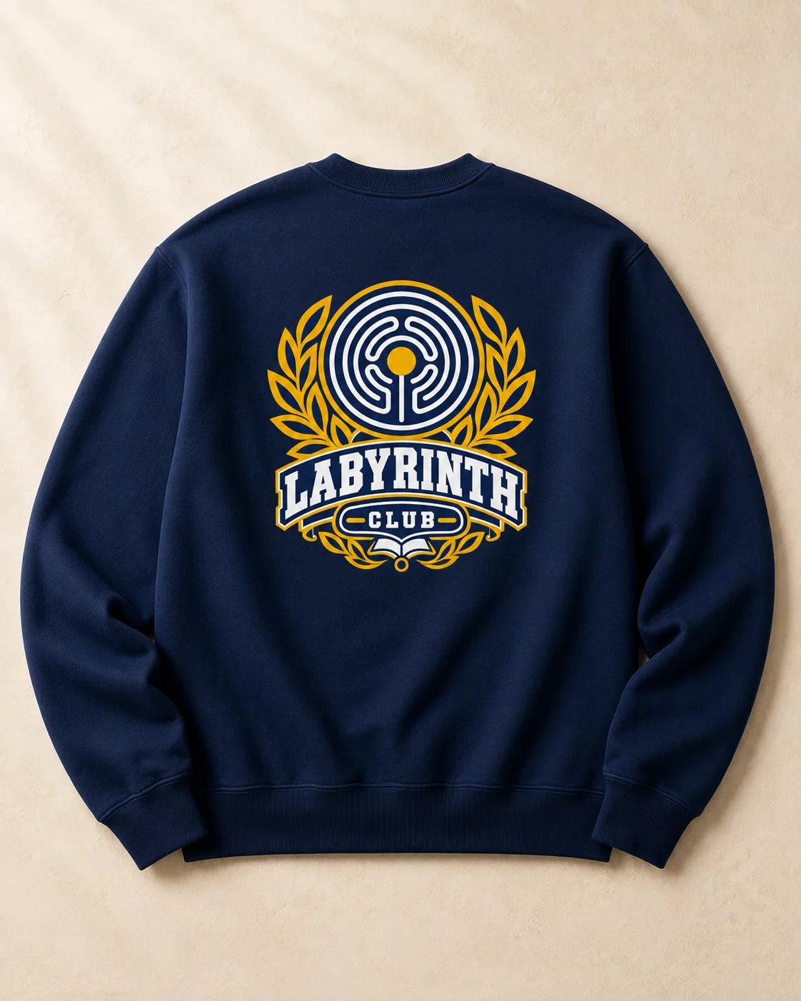 A navy blue crewneck sweatshirt shown from the back, featuring a large graphic print of a maze emblem, laurel leaves, and the text 'LABYRINTH CLUB' in yellow, white, and blue on a beige textured background.
