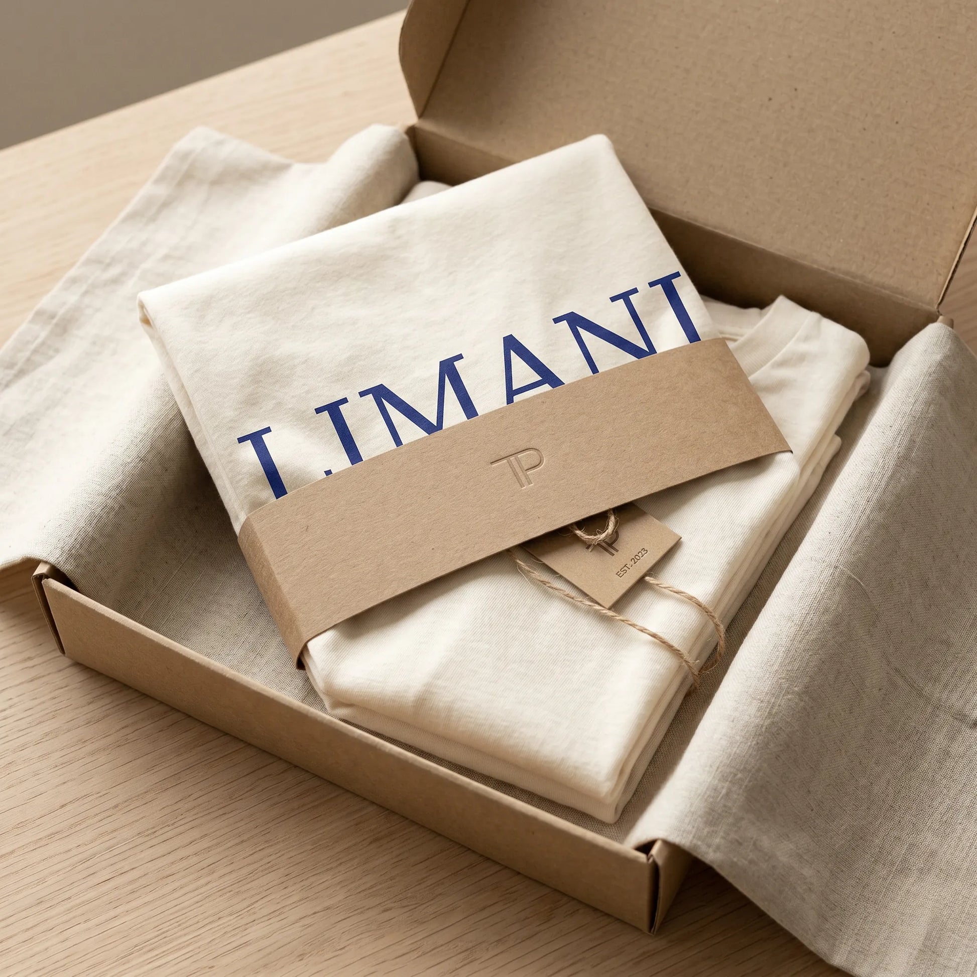 Folded beige fabric with 'LIMANI' branding in a cardboard box