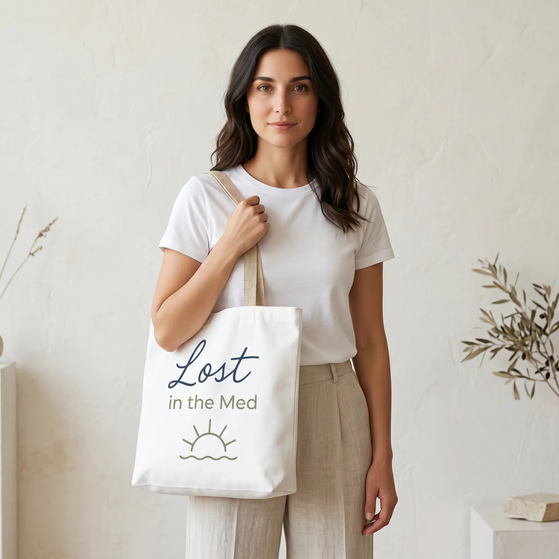 Woman holding a tote bag with 'Lost in the Med' text against a neutral background