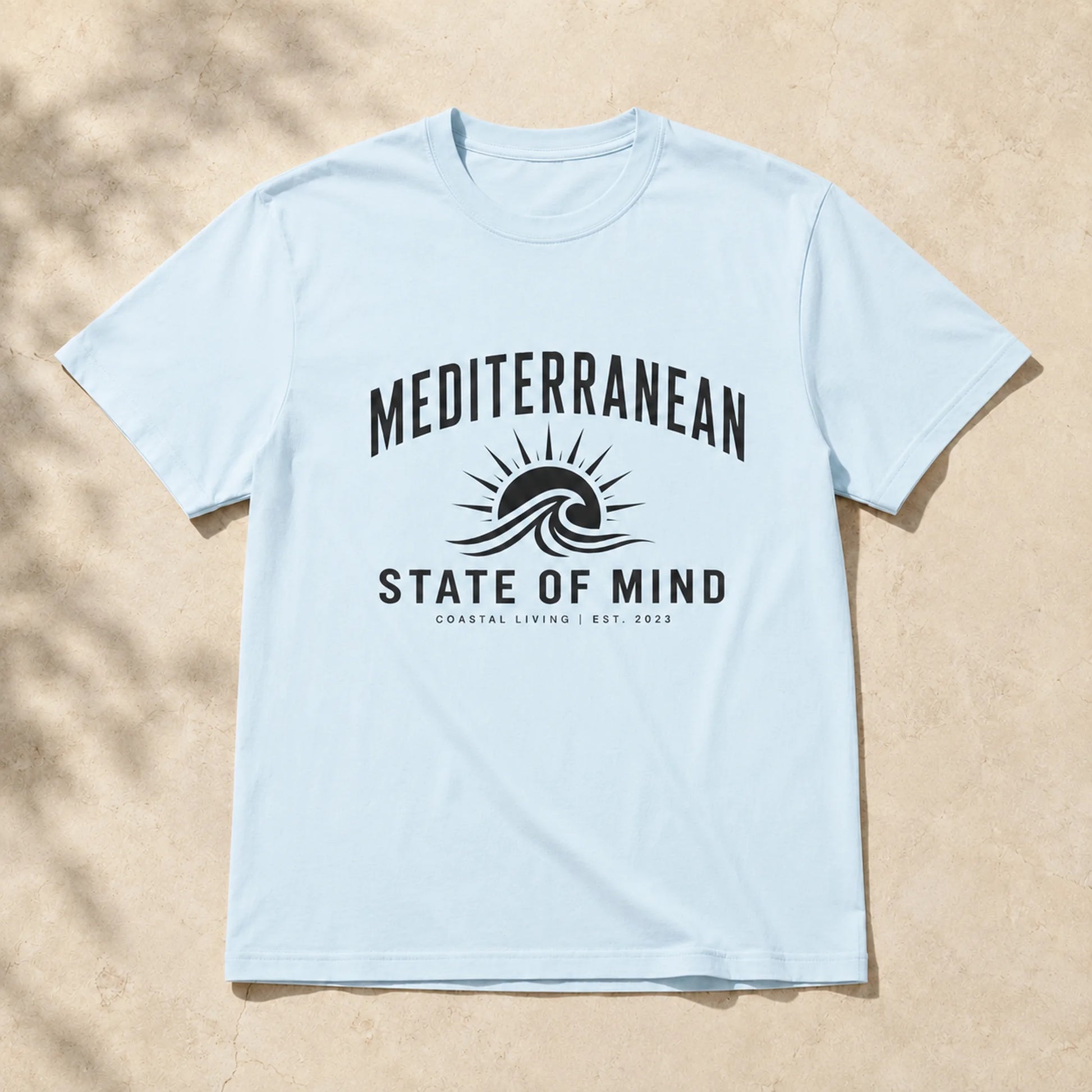 Light blue t-shirt with 'Mediterranean State of Mind' design on a beige background