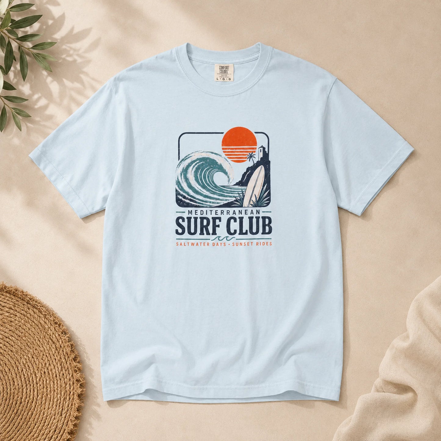 Light blue t-shirt with Mediterranean Surf Club graphic on a beige background