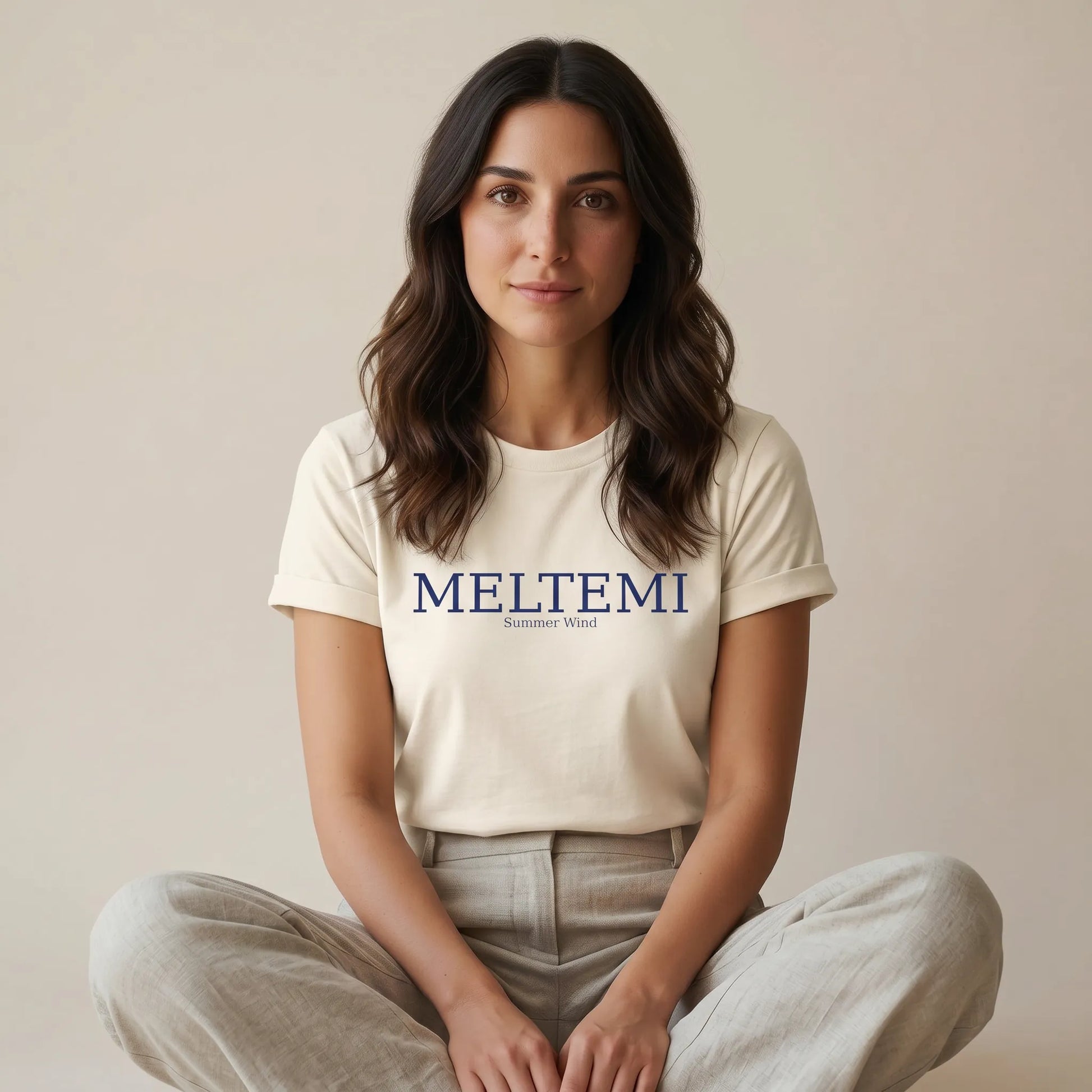 Woman wearing a white t-shirt with 'MELTEMI' logo on a beige background