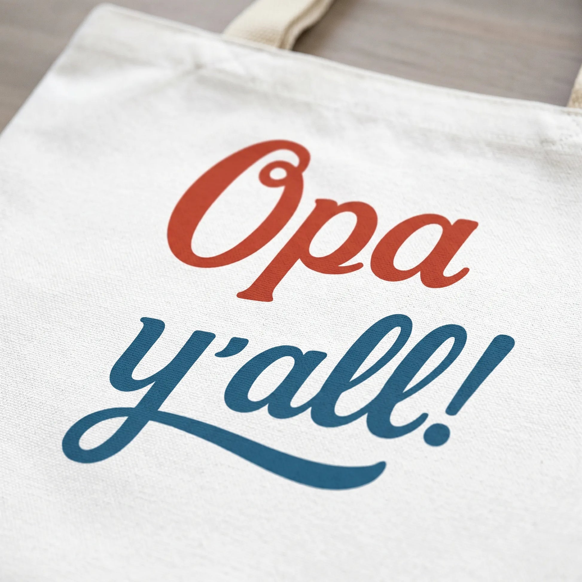 Close-up detail of the Opa y’all Greek summer tote bag print showing the red and blue phrase design clearly