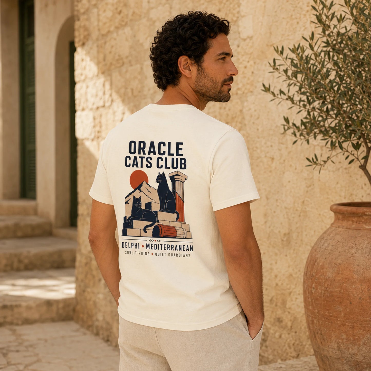 Man wearing a 'Oracle Cats Club' t-shirt with a cat-themed design outdoors.