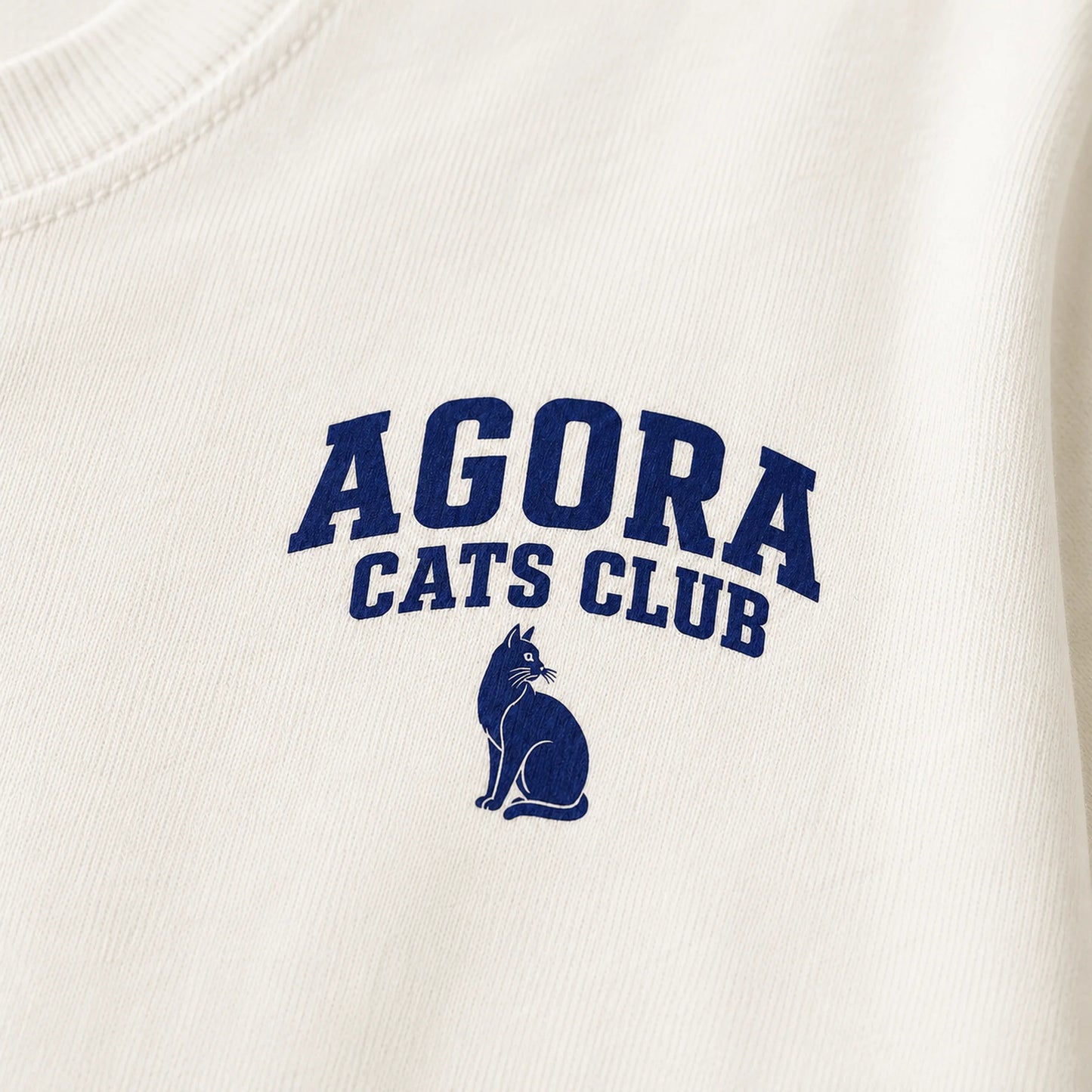 White sweatshirt with 'Agora Cats Club' text and cat logo in blue.