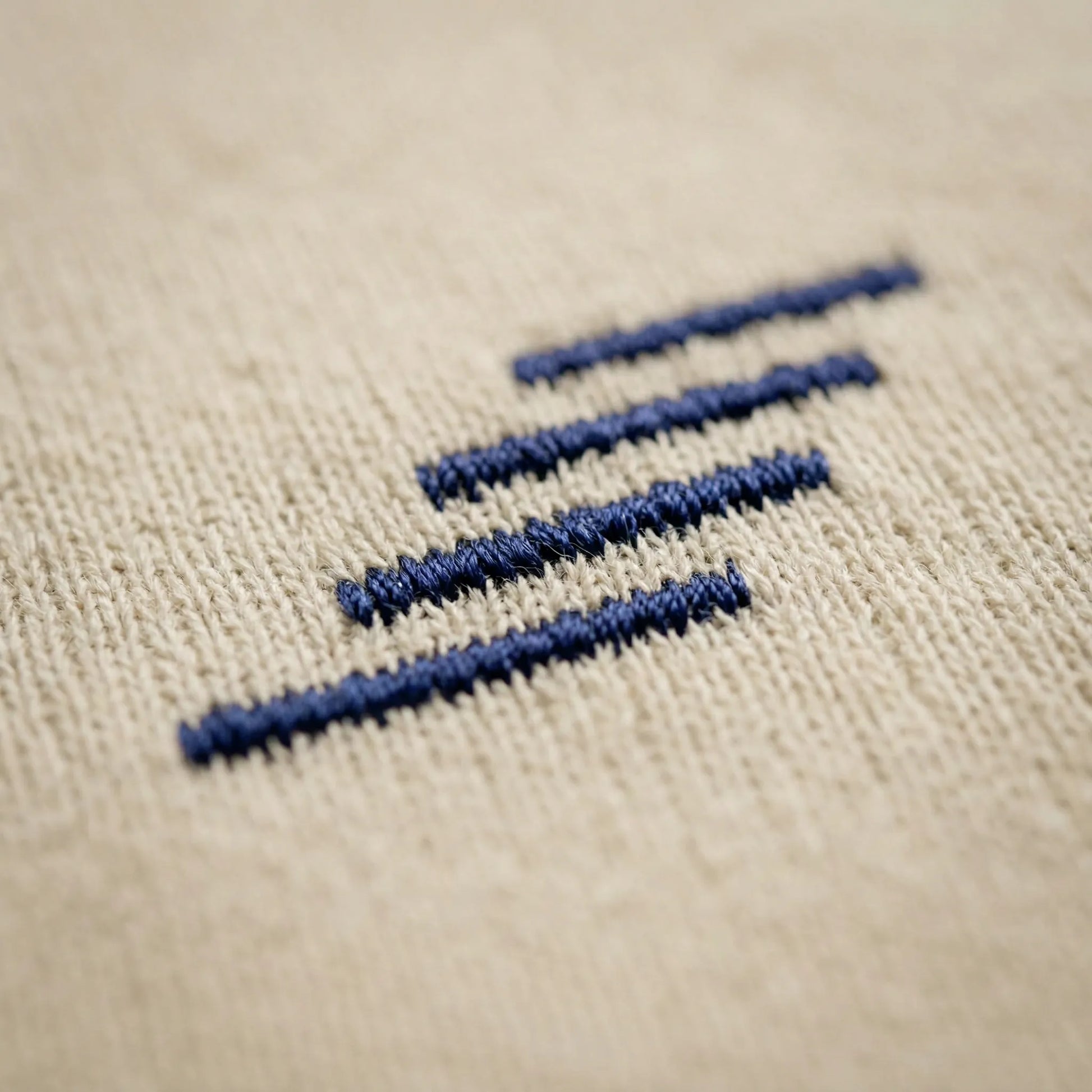 Embroidered equal sign on beige fabric