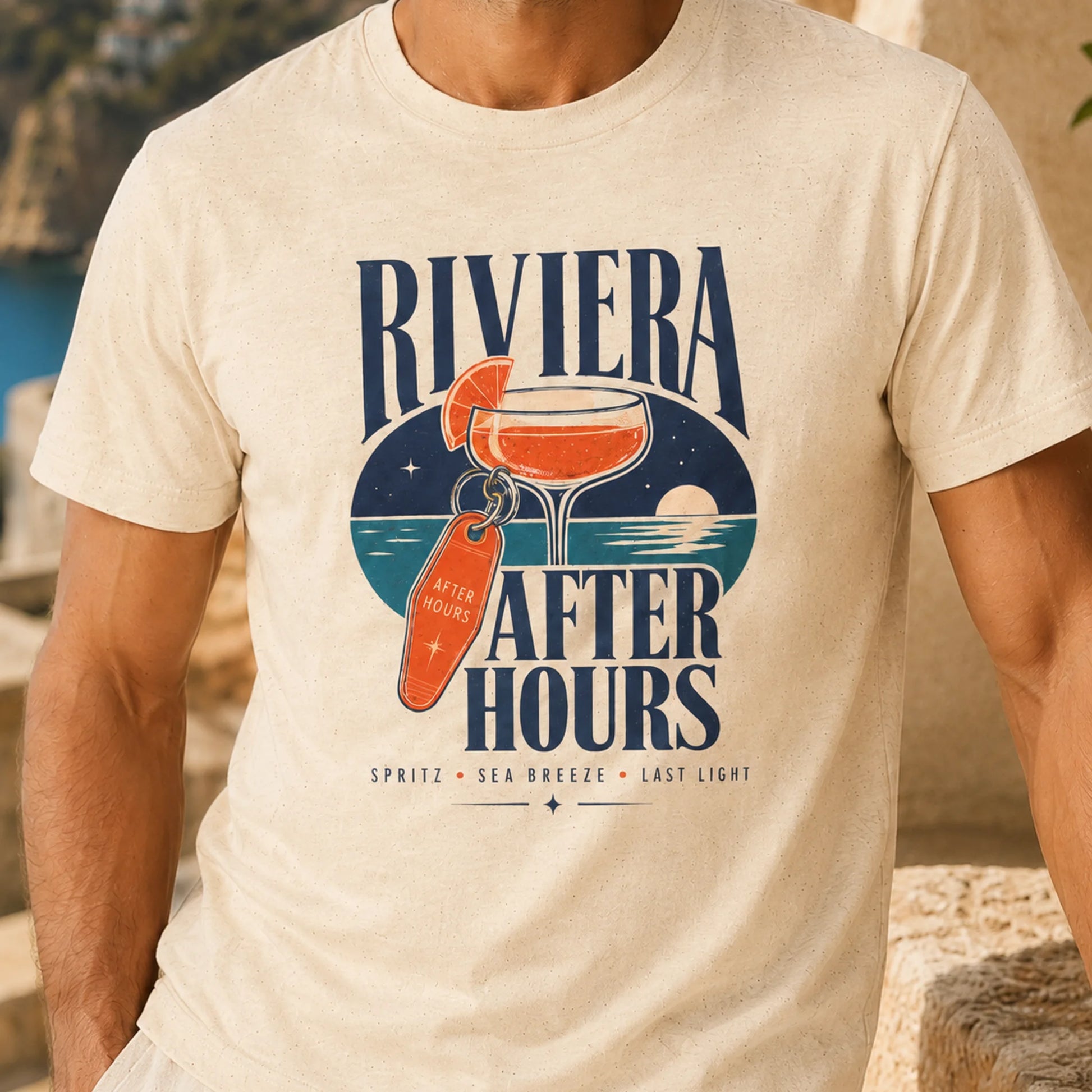 TP HERO: A man wearing a cream-colored t-shirt with a distressed graphic that reads 'RIVIERA AFTER HOURS' in navy blue, featuring an illustration of a cocktail and a tropical drink tag.