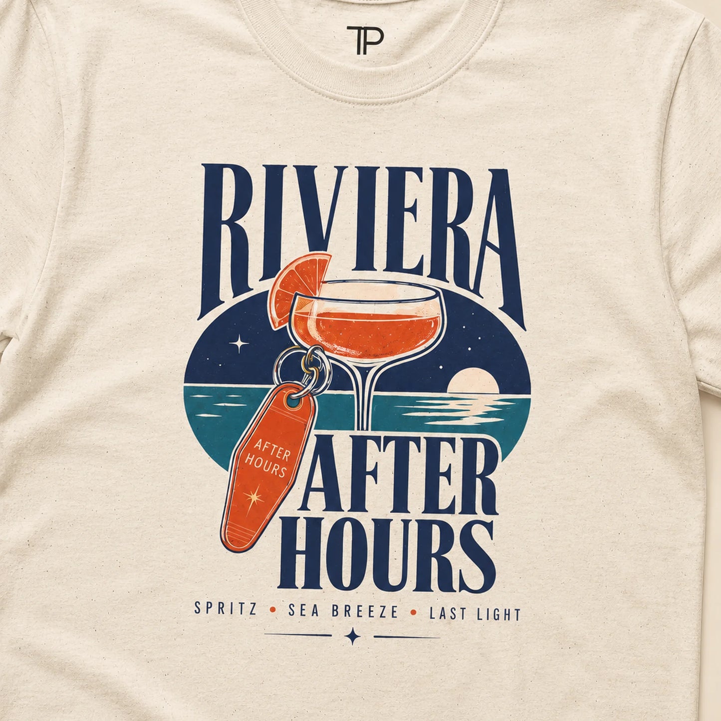 A close-up of a cream-colored t-shirt featuring a retro graphic print. The design displays the text 'RIVIERA AFTER HOURS' in navy blue, with an illustration of an orange cocktail and a key labeled 'AFTER HOURS' over a circular blue and teal night-sky and ocean motif.