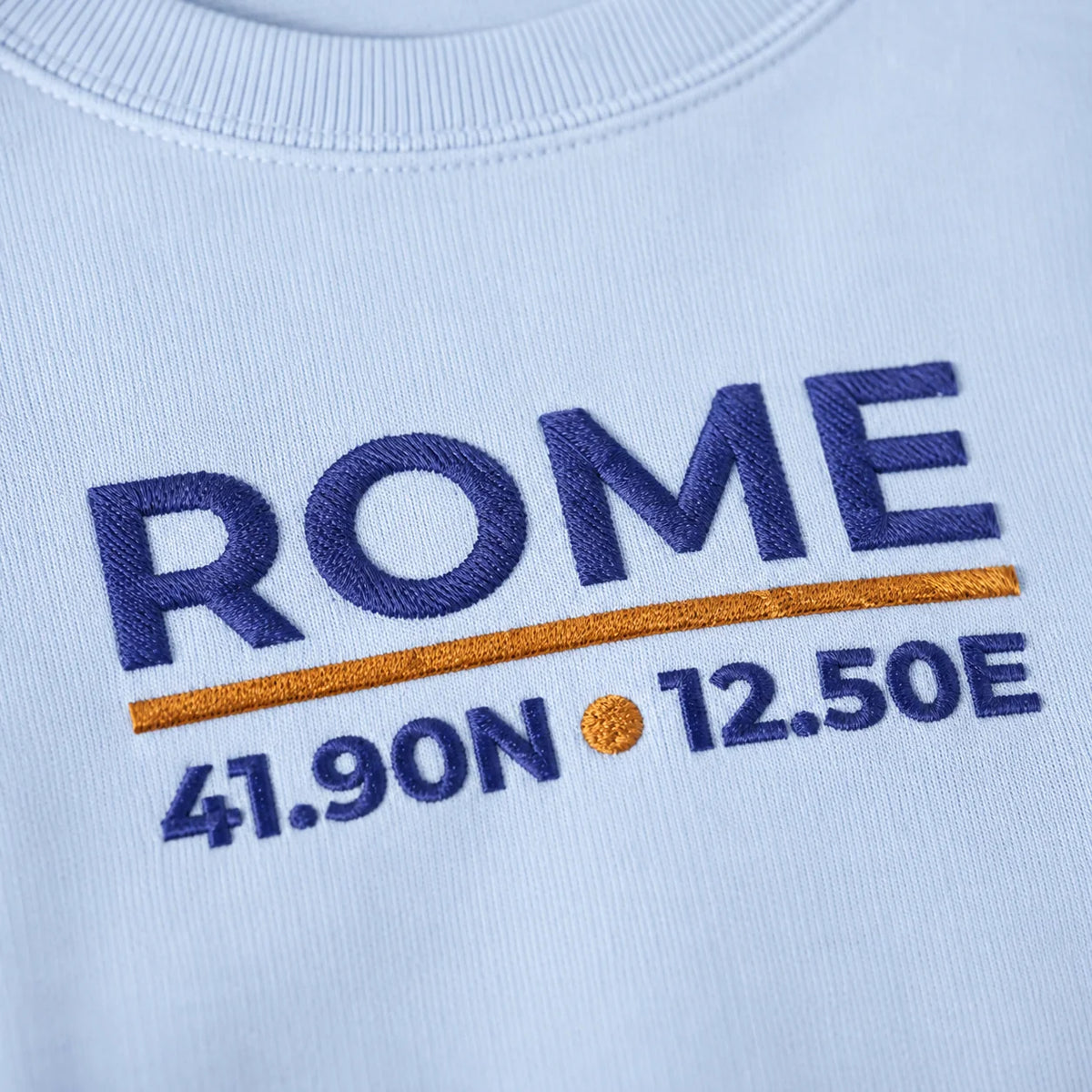 Close-up of the Light Blue Rome Coordinates Embroidered Sweatshirt embroidery and stitch detail.