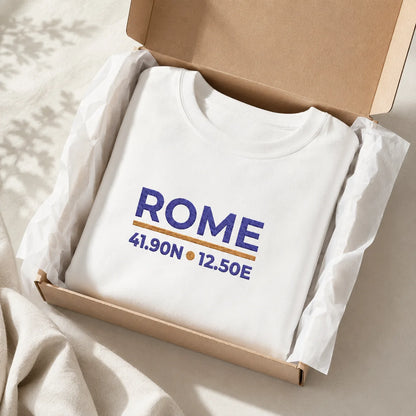Folded White Rome Coordinates embroidered crewneck sweatshirt with navy and gold city-coordinate design, prepared in gift-style packaging.