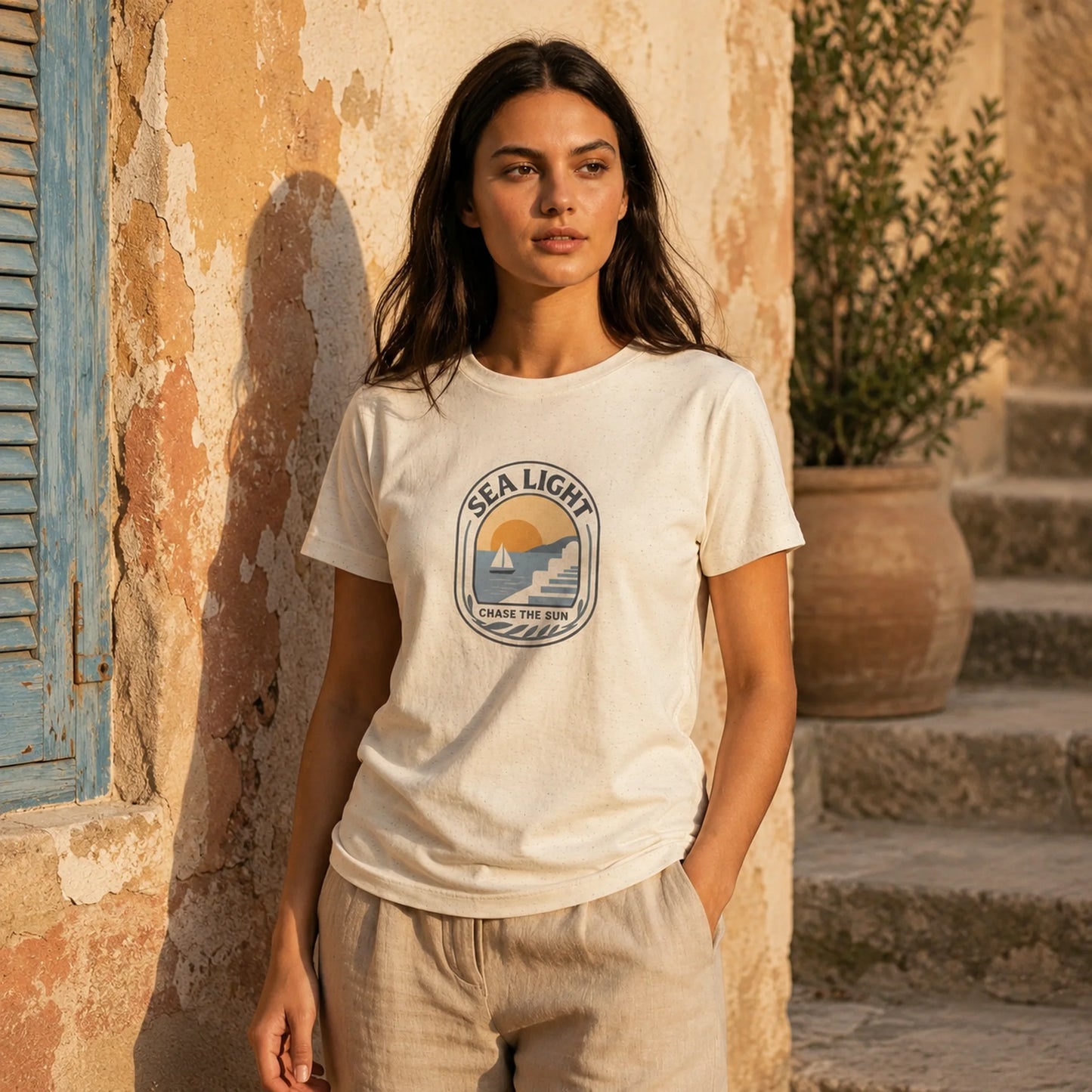Woman wearing a 'Sea Light' t-shirt standing in front of a rustic wall.