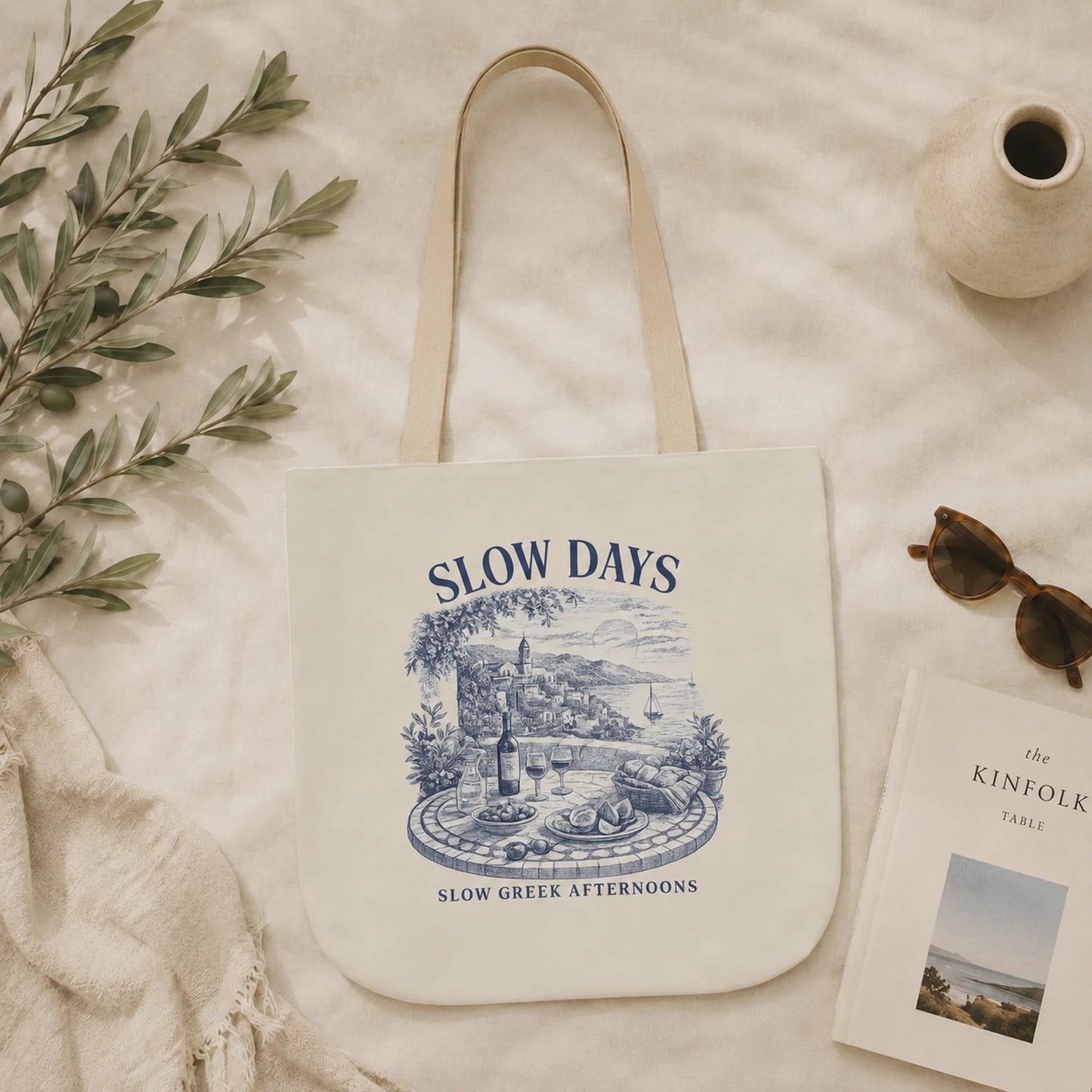 Tote bag with 'Slow Days' design on a soft surface with a vase and sunglasses.