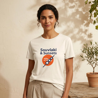 Woman wearing a white t-shirt with 'Souvaki & Sunsets' design, standing against a neutral background with a plant.