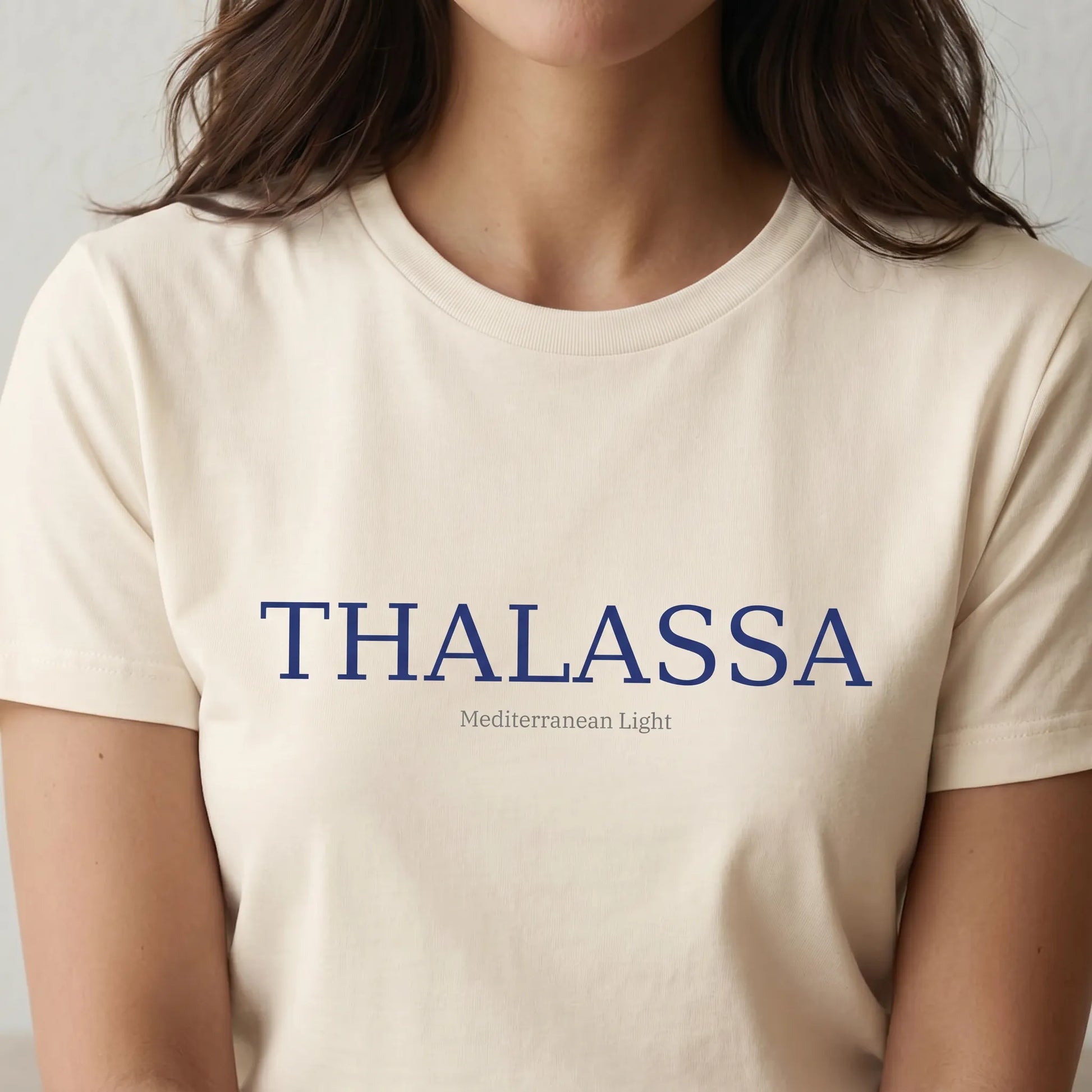 TP HERO: Person wearing a beige t-shirt with 'THALASSA' printed on it against a neutral background