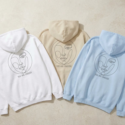 Abstract Muse Face You Are Enough hoodies in white sand and light blue laid out with back prints visible