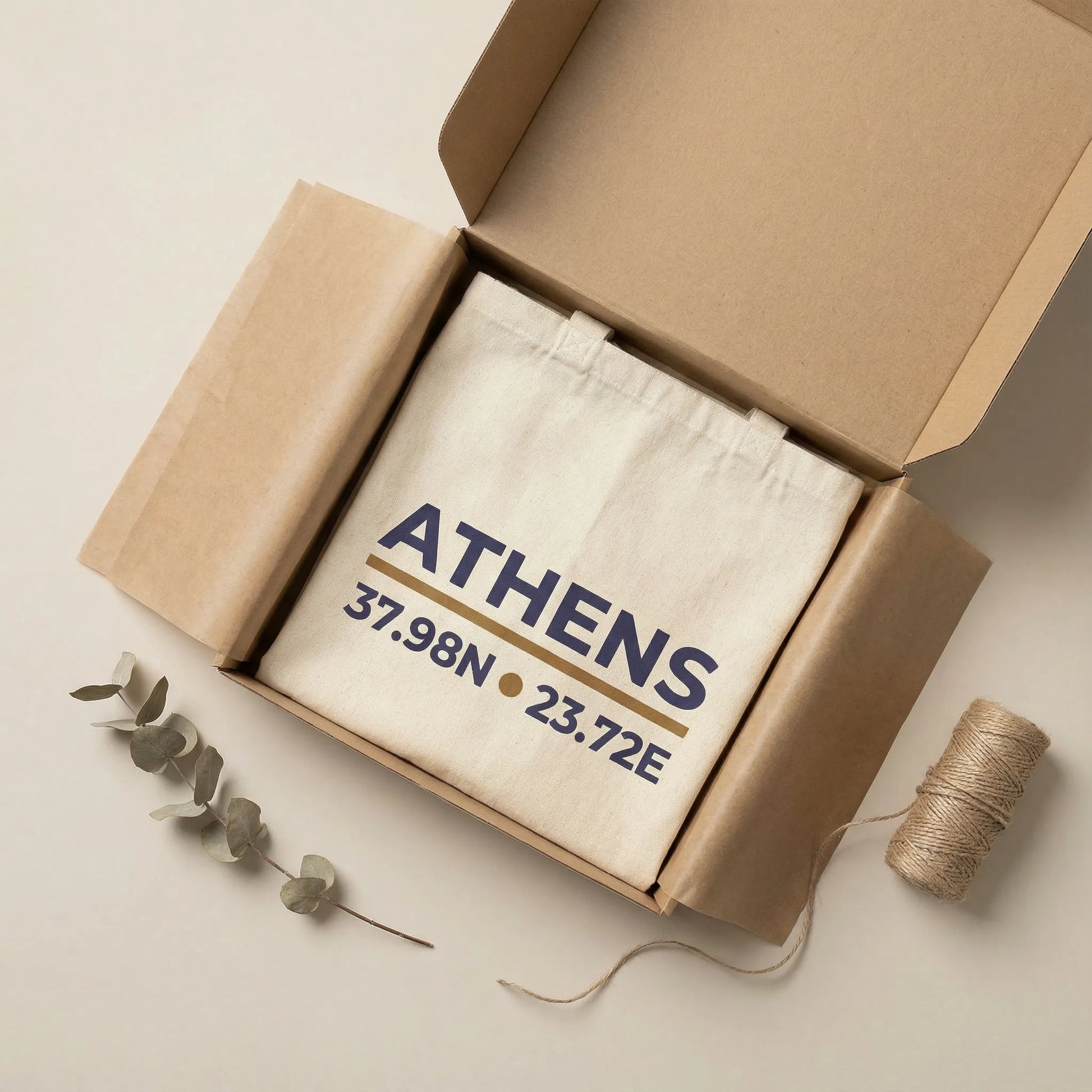 Athens coordinates tote bag packaging presentation on a light neutral surface.