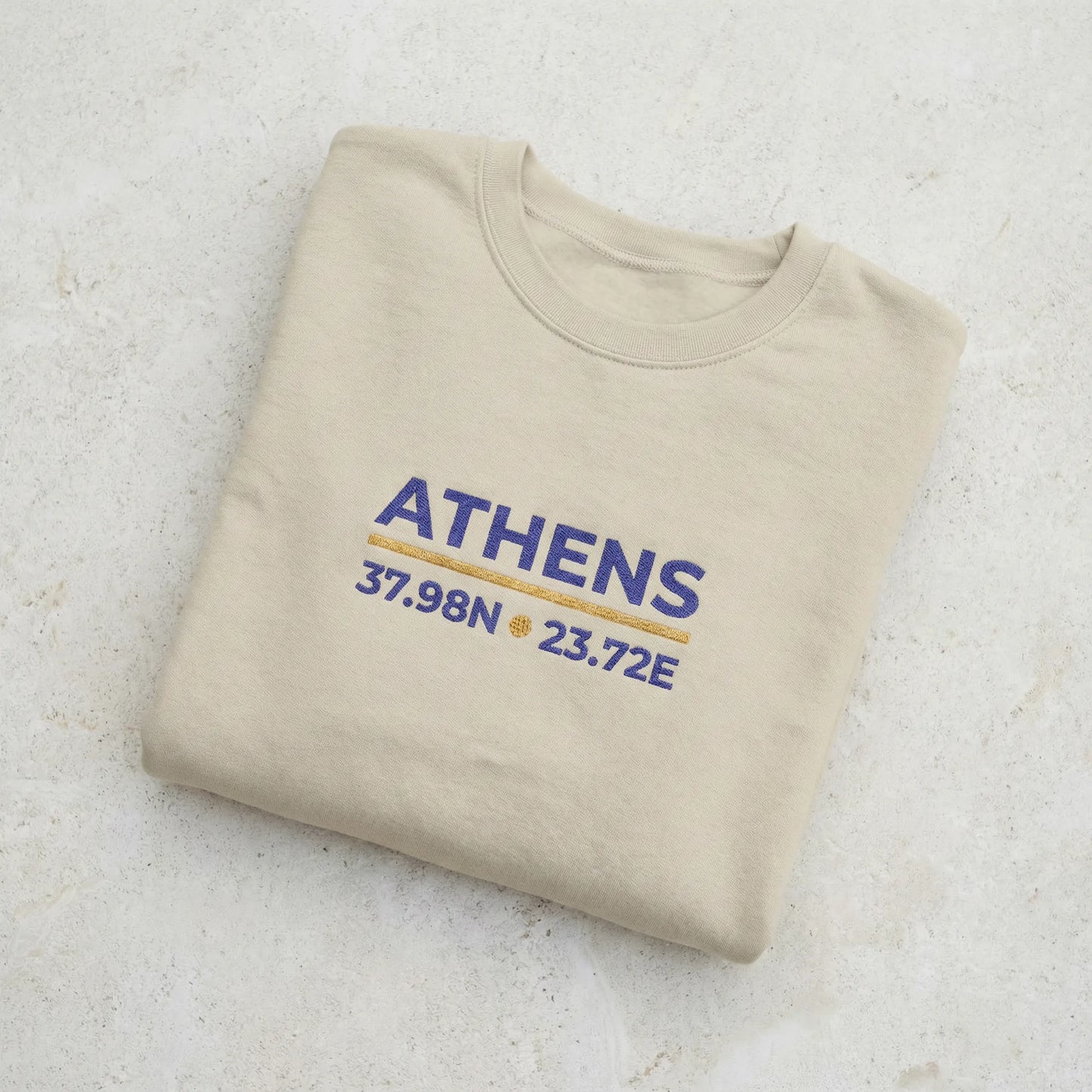 Folded sand crewneck sweatshirt showing fabric texture and embroidery detail