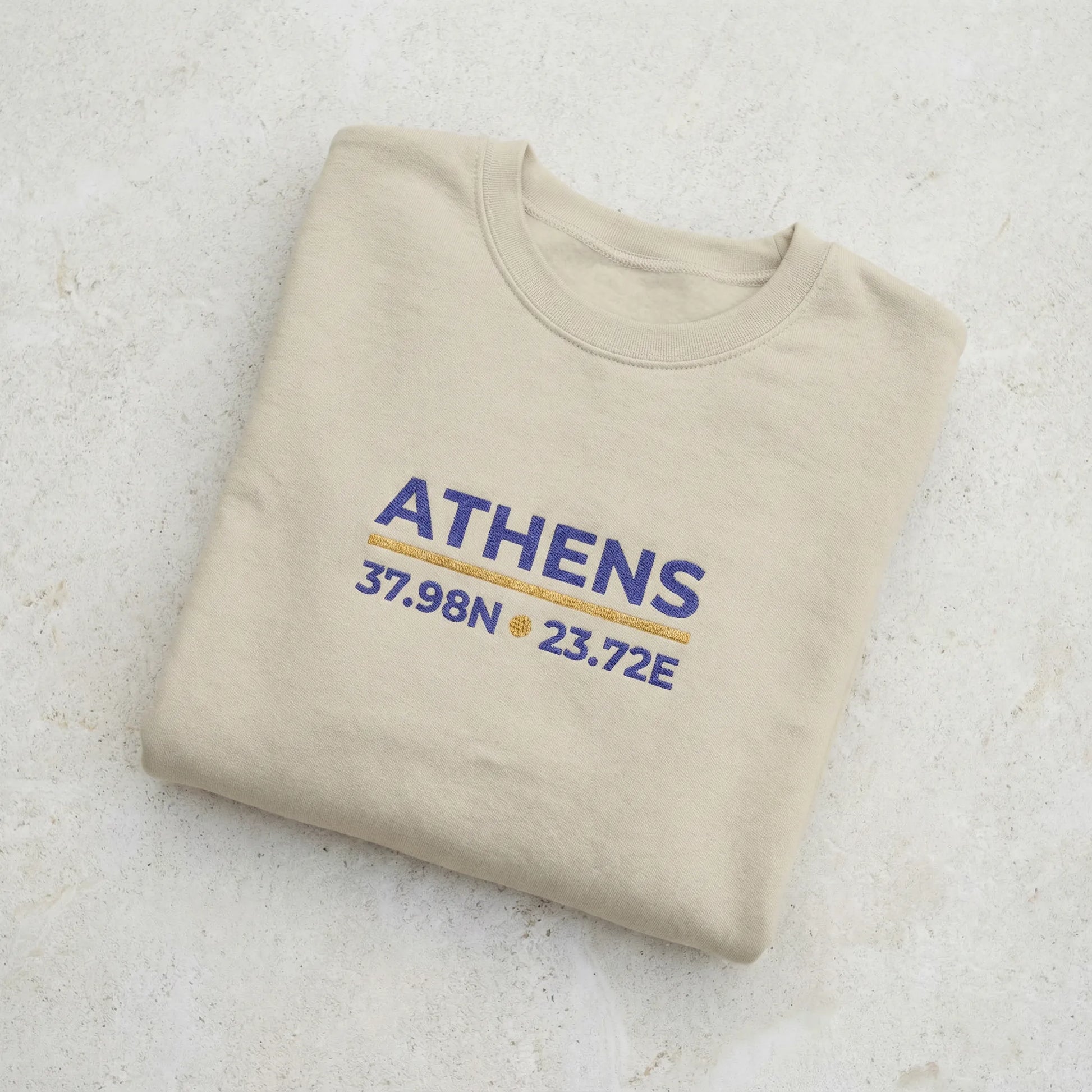 Folded sand crewneck sweatshirt showing fabric texture and embroidery detail