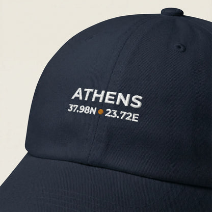 Navy blue cap with 'ATHENS' and coordinates embroidered on a beige background