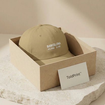 Beige cap with 'Barcelona' text in a cardboard box, featuring ToldPrint branding.