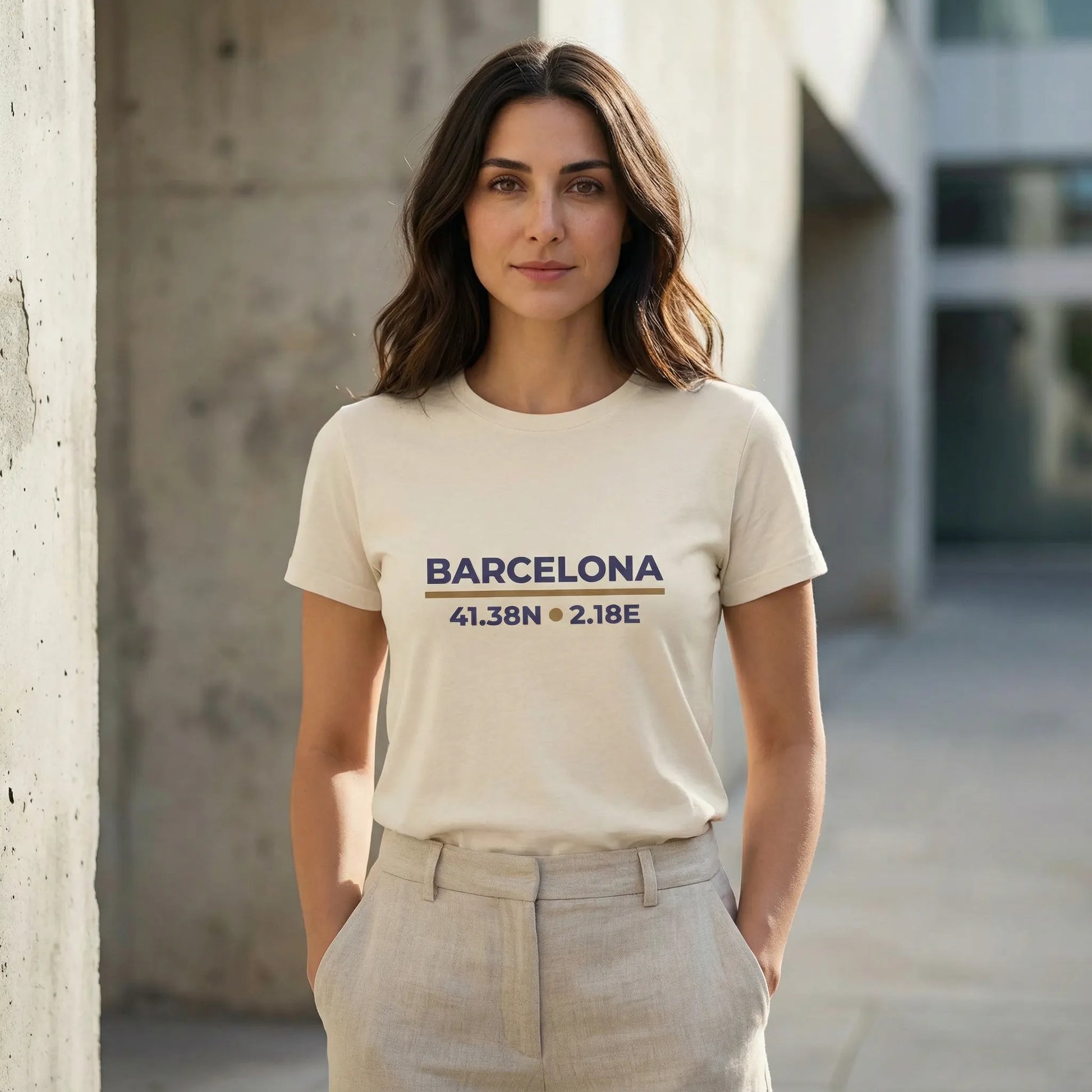Woman wearing a t-shirt with 'Barcelona' and coordinates, standing against a concrete wall.