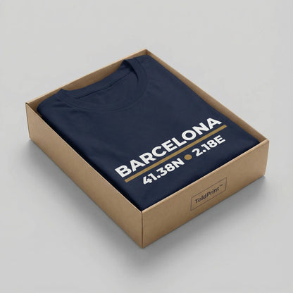 Navy blue t-shirt with 'Barcelona' and coordinates printed on it, inside a cardboard box.